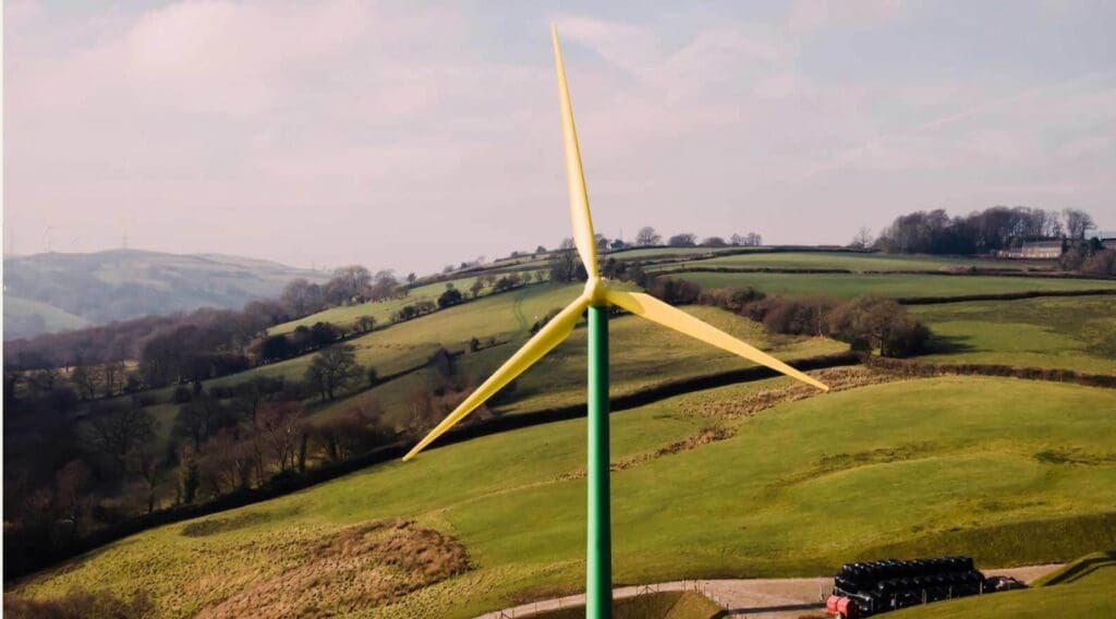 A windmill towers against a backdrop of rolling green fields