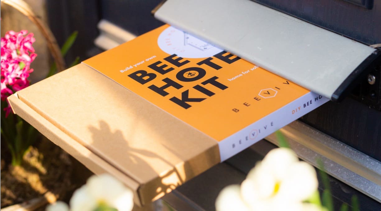A bee hotel DIY kit being posted through a door