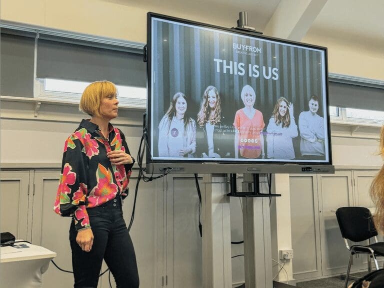 woman stood beside TV screen showcasing her business.