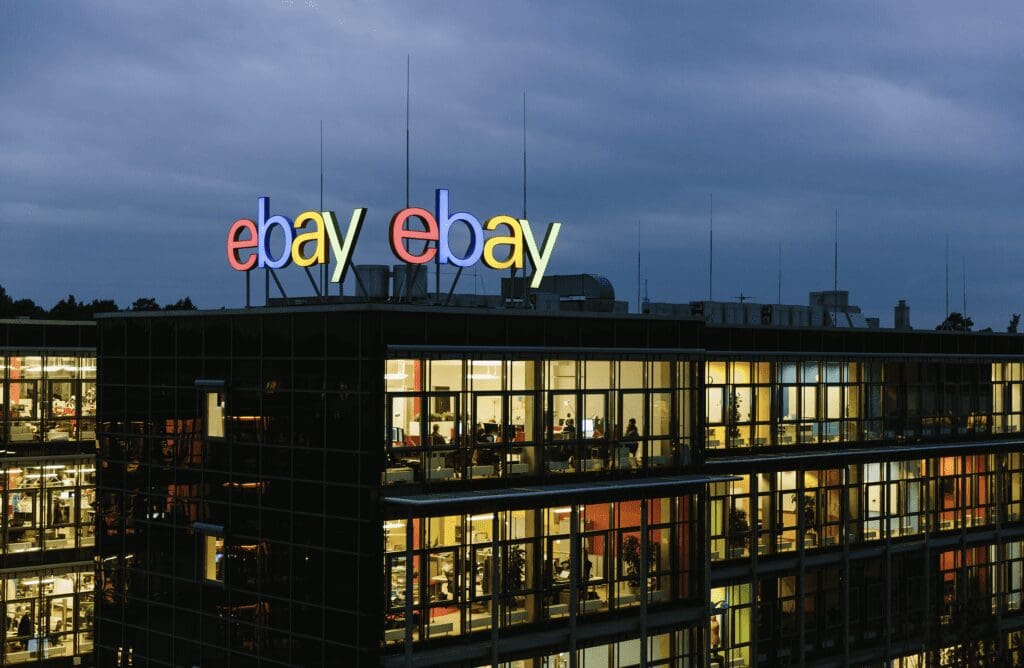 eBay office lit up against a moody dark sky with eBay logo in lights on top of the building.