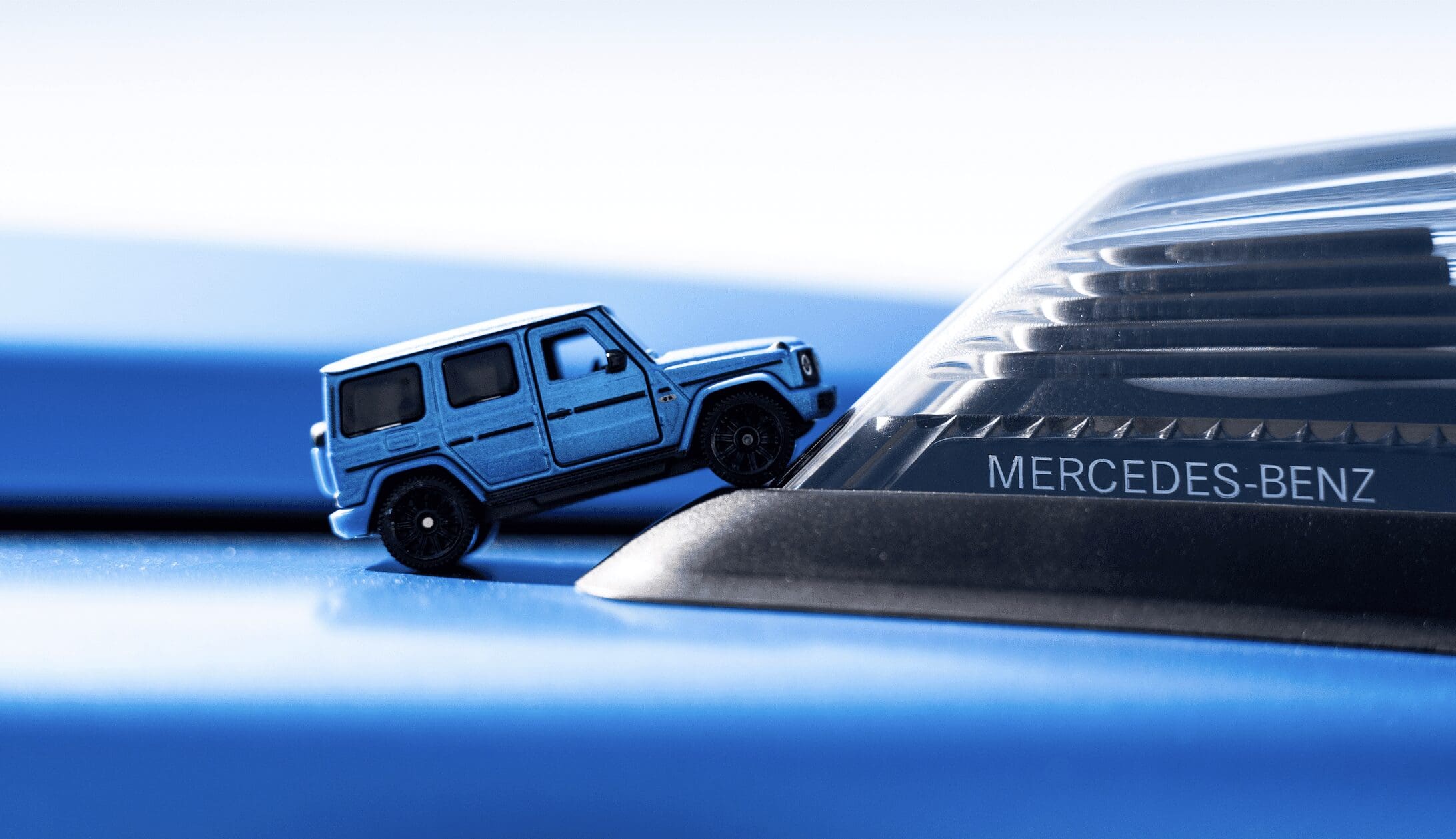 stylish metallic blue backdrop with die cast Matchbox Meades-Benz in foreground