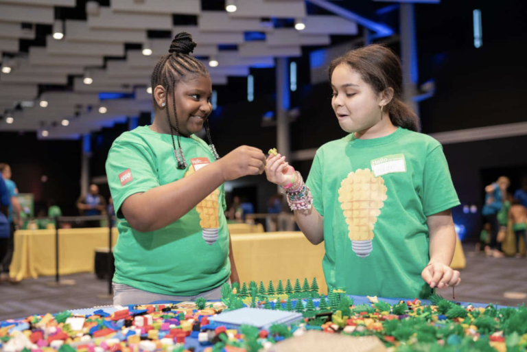 two children dressed in green t shirts play with LEGO bricks.