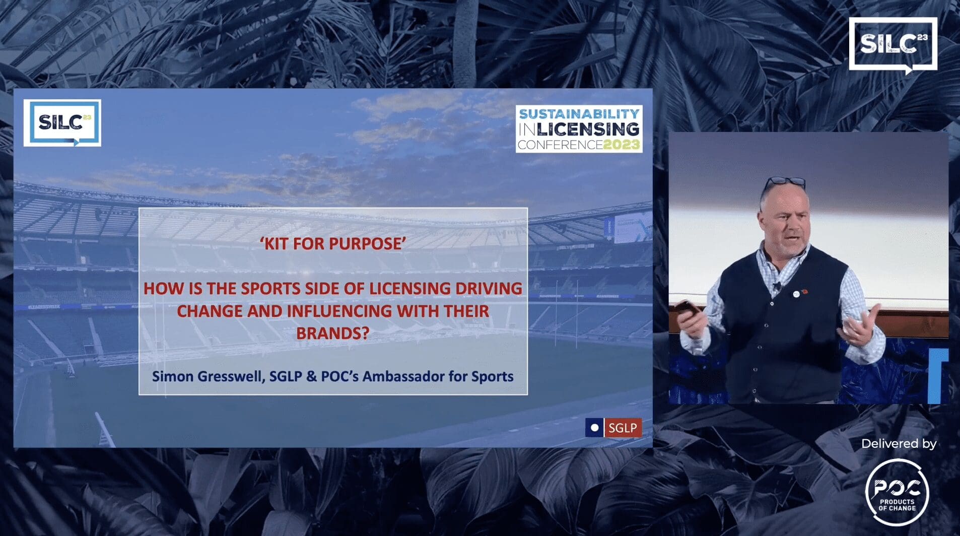 Simon Gresswell stands on SILC stage next to screen of presentation title