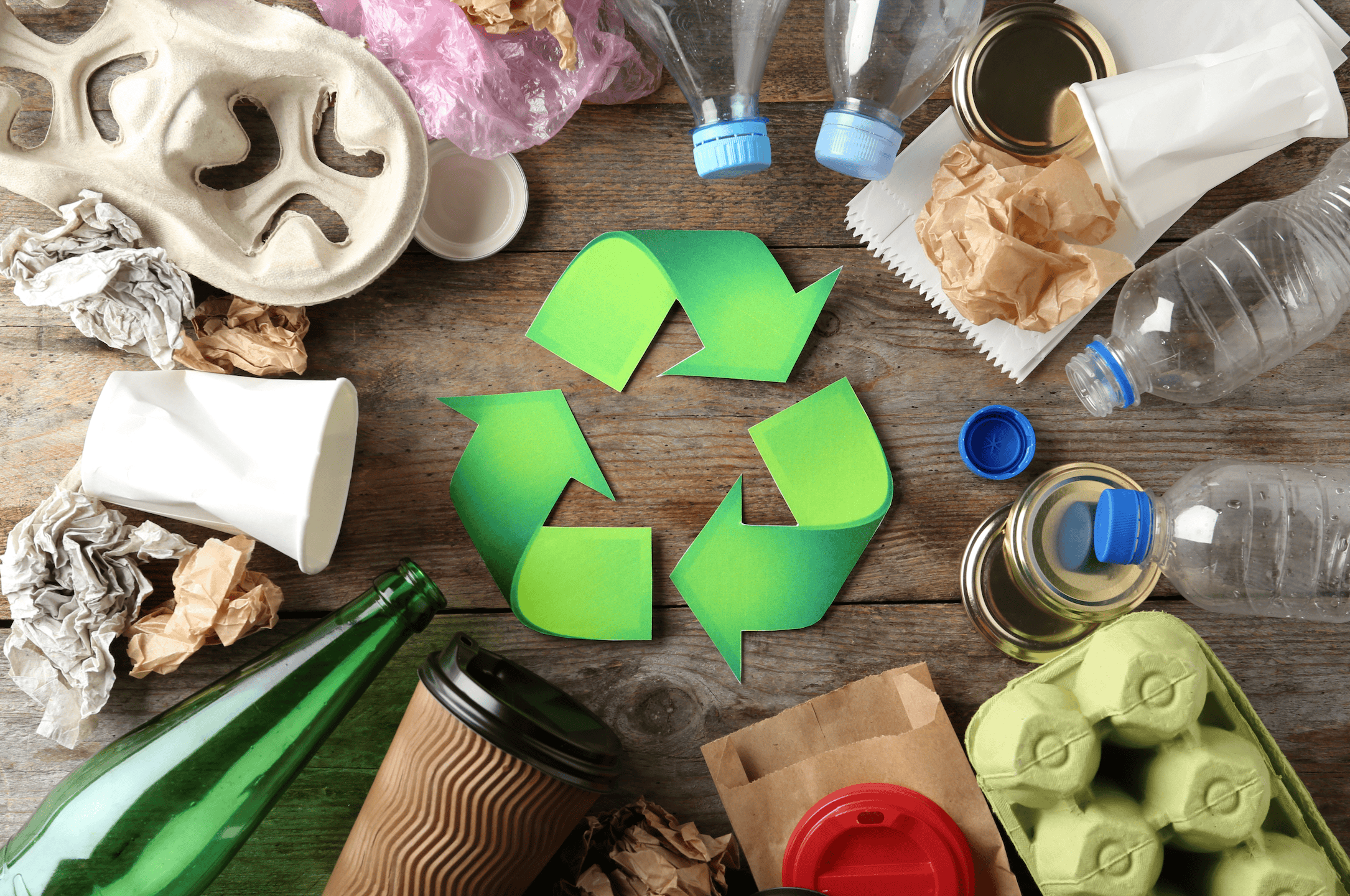 collection of packaging made from different materials gathered on a table with a recycling logo in the middle