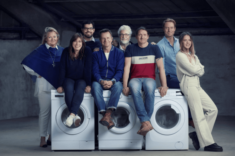 The Cleaner Seas Group team - men and women - grouped together around a washing machine
