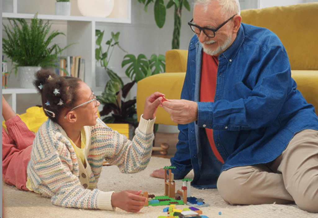 Young girl plays with lego bricks with her grandfather.