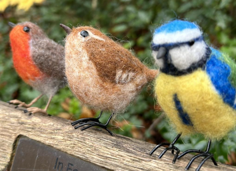 Three little birds, a robin, a starling, and a bluebird all made from wool
