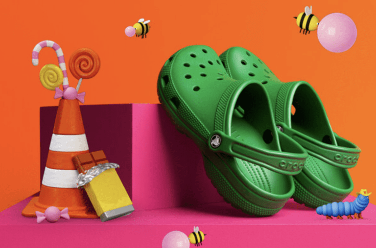 promotional image of pair of green crocs on a pink and orange background