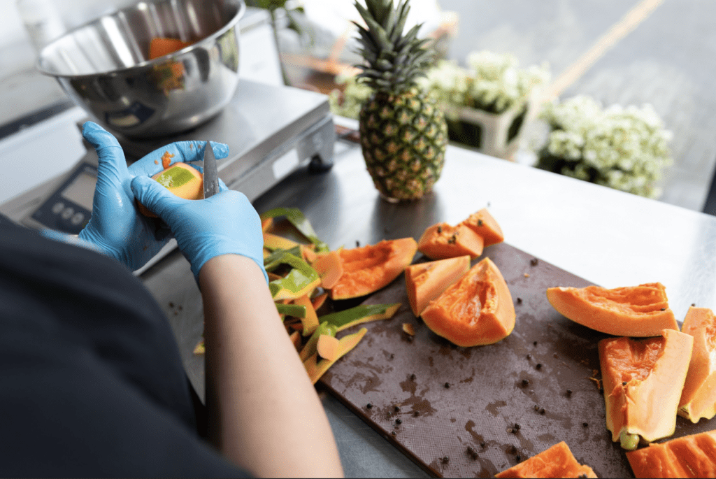 chopping board with chopped up fruit and a pineapple
