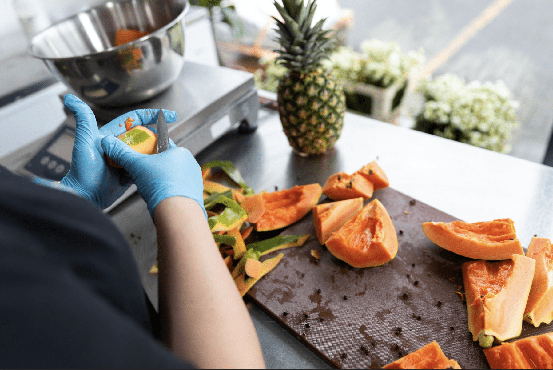 chopping board with chopped up fruit and a pineapple
