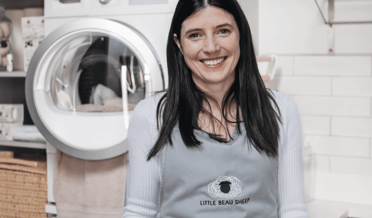 Little beau Sheep founder, Sarah Turner poses in front of tumble dryer in branded apron