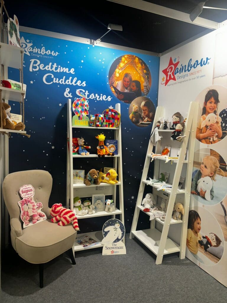 Rainbow Designs stand with chairs and shelves full of children's toys.