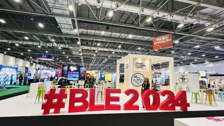Large letters spelling #BLE2024 standing in front of the show floor. Helena Mansell-Stopher poses with the letters holding the POC logo