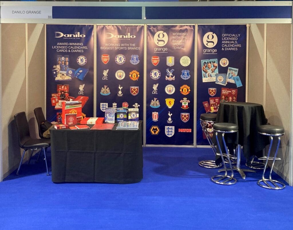 Danilo stand, with table and backdrop of sport team logos.