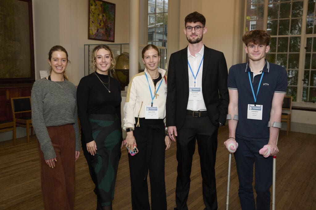 A group of five people standing in a row smiling at the camera