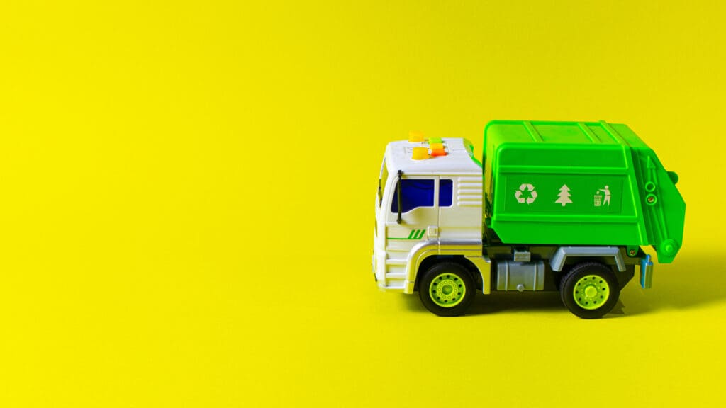 A plastic toy refuse truck on a yellow background