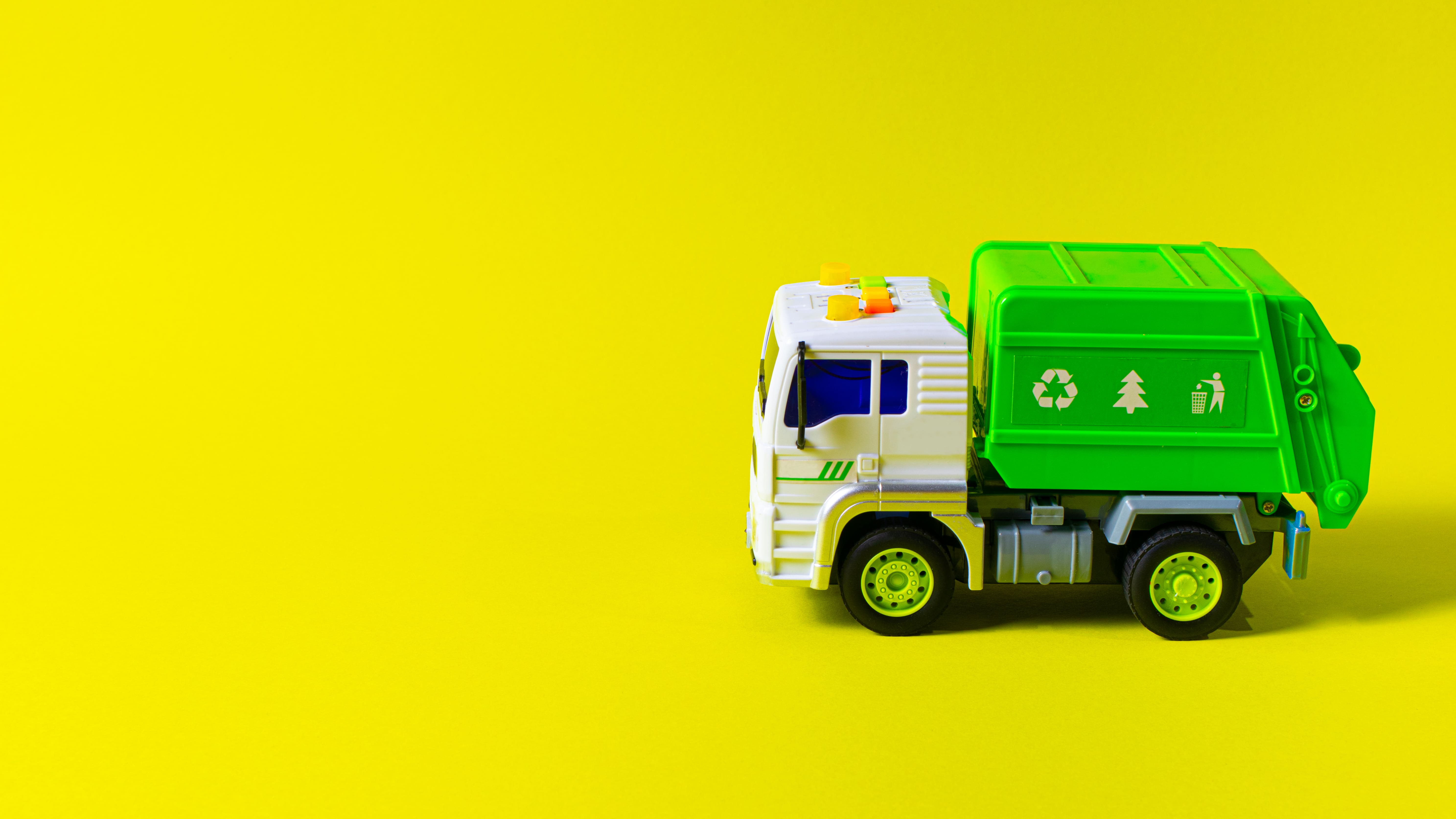 A plastic toy refuse truck on a yellow background