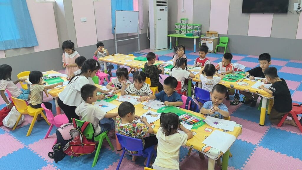A group pf children sitting around tables in a playroom
